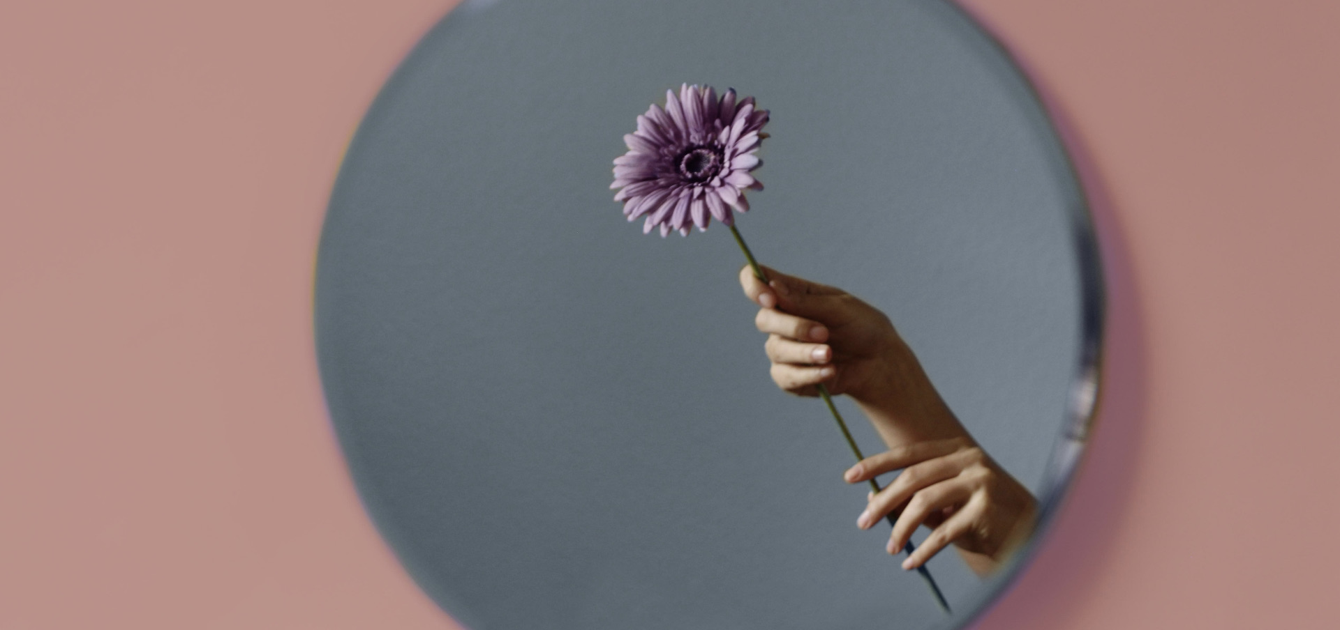 a person holding a flower and looking in the mirror