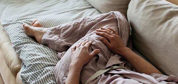 woman lying on a couch not feeling well