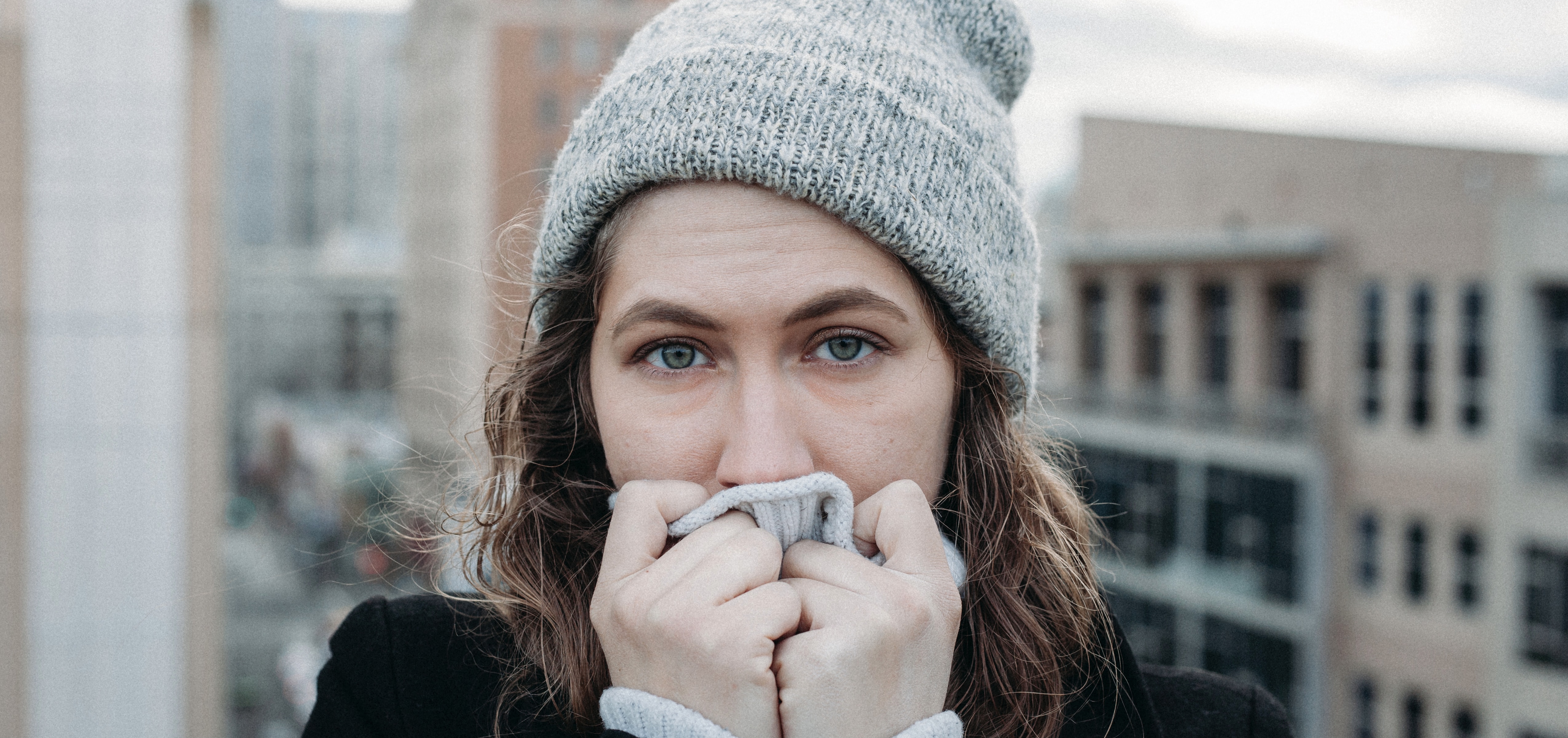 woman on a balcony wearing a winter coat and hat