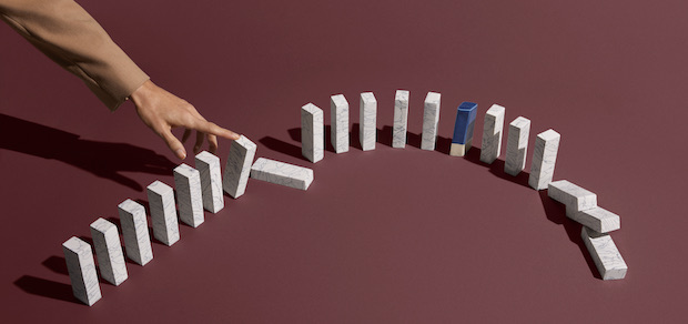 hand knocking down dominoes