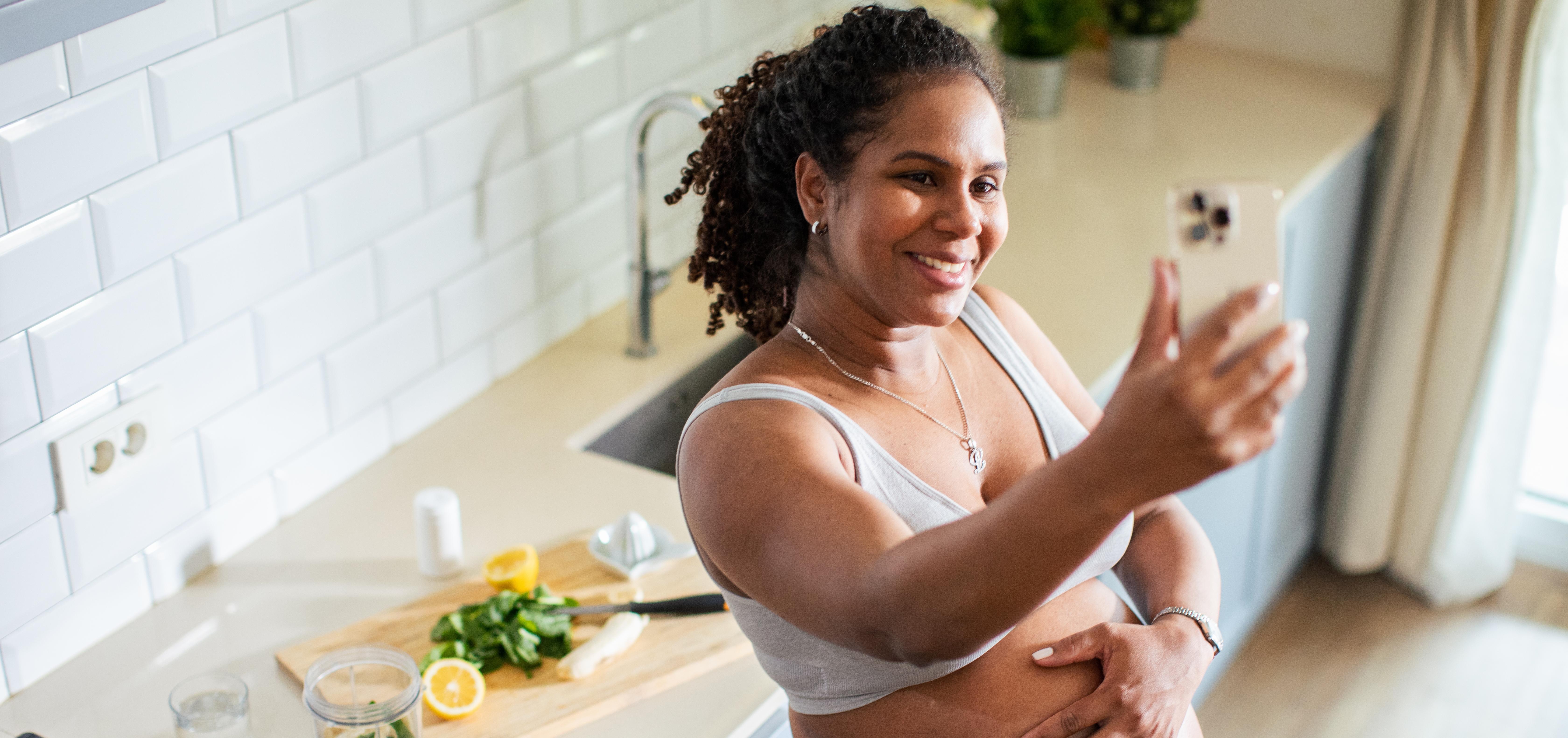 pregnant woman taking a selfie in her kitchen