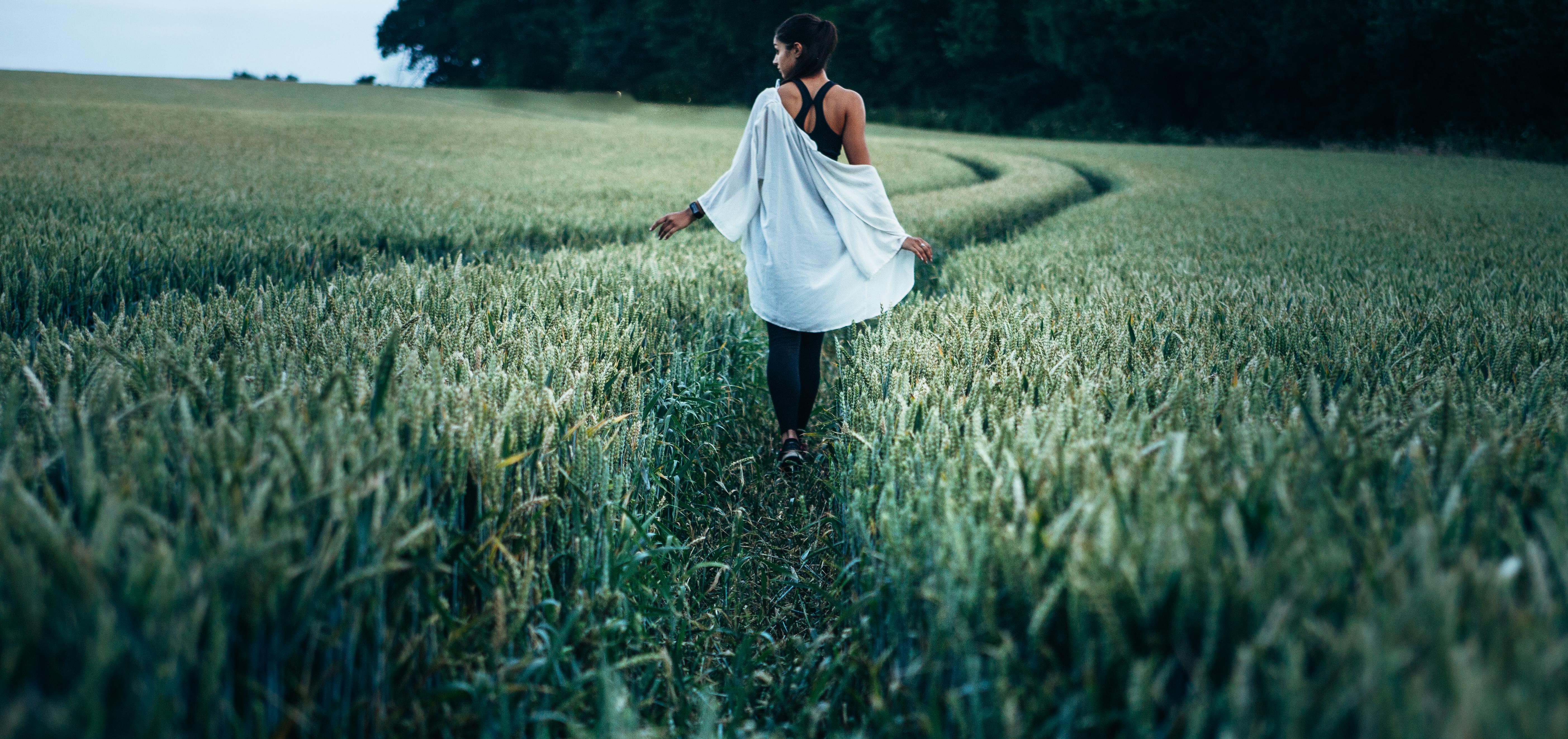 woman walking through tall green grass