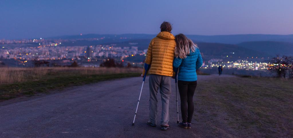 man on crutches with a woman leaning her head against his shoulder