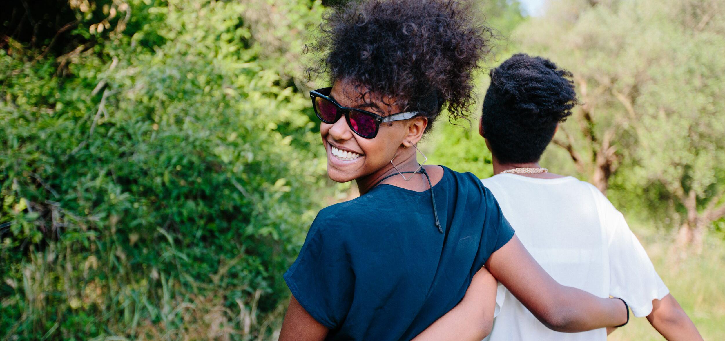 Two friends walking outdoors with arms casually around each others waists