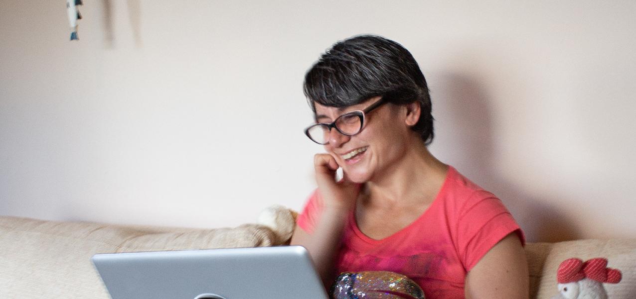 smiling woman sitting on the sofa with her laptop