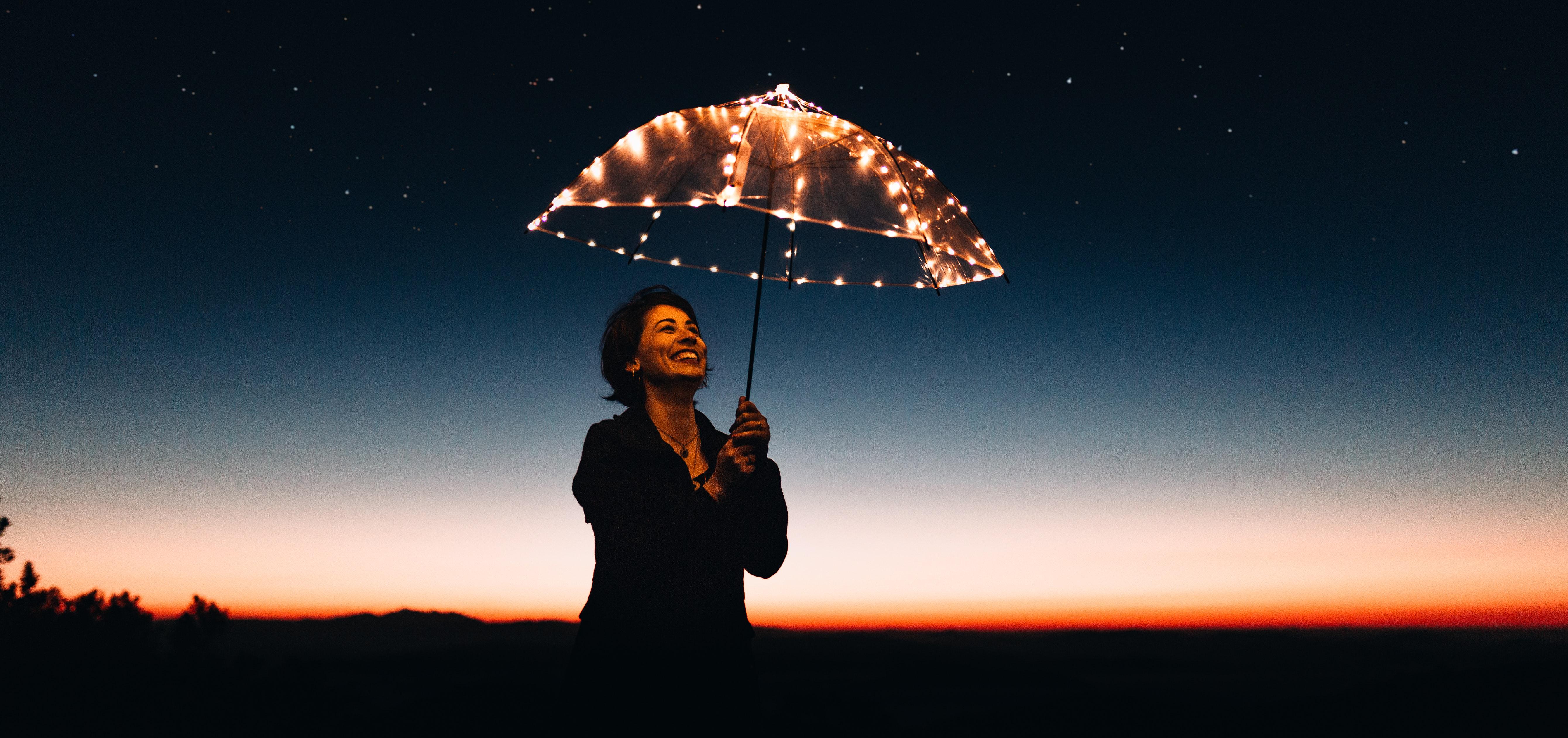 smiling woman holding a lighted umbrella outdoors