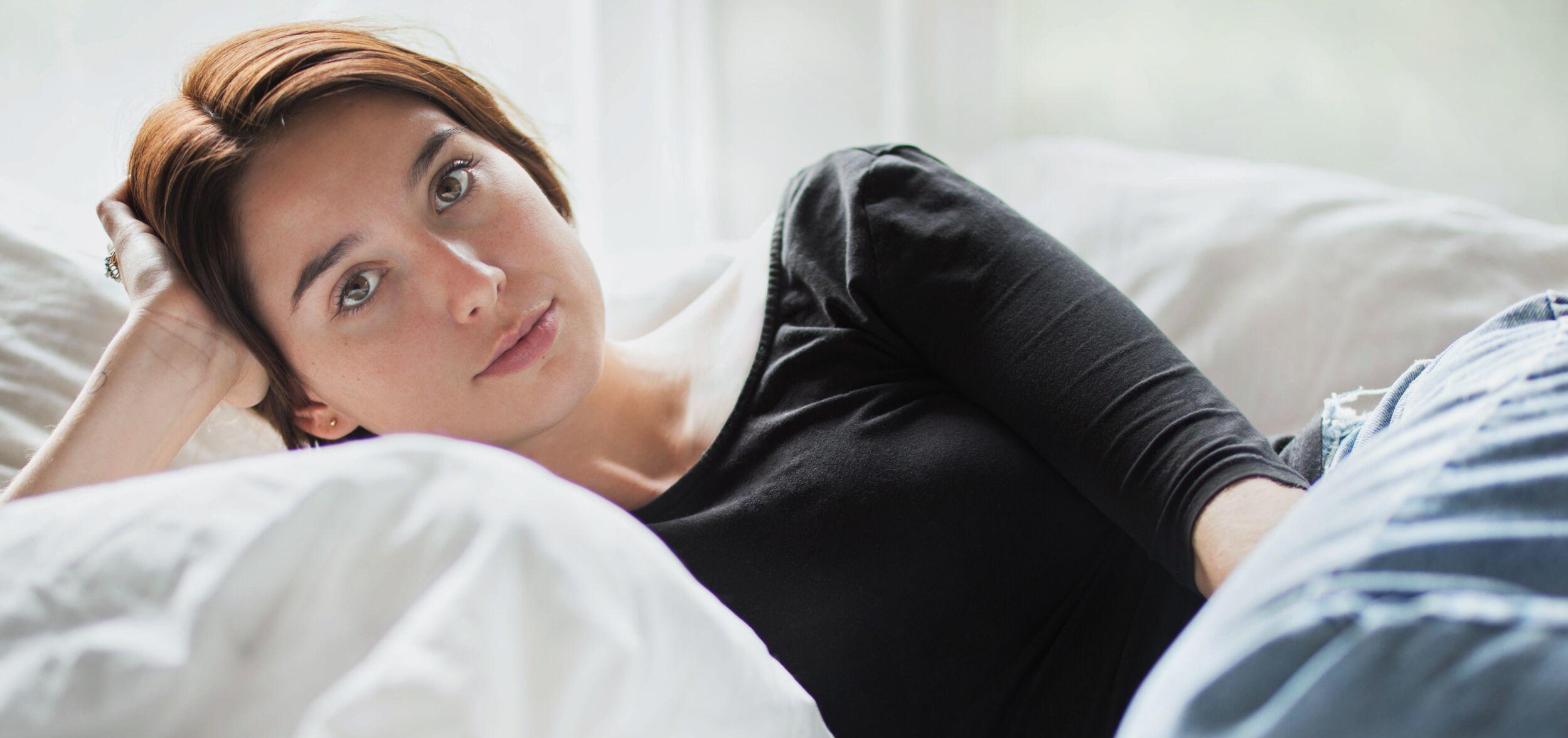 Woman lying on bed deep in thought