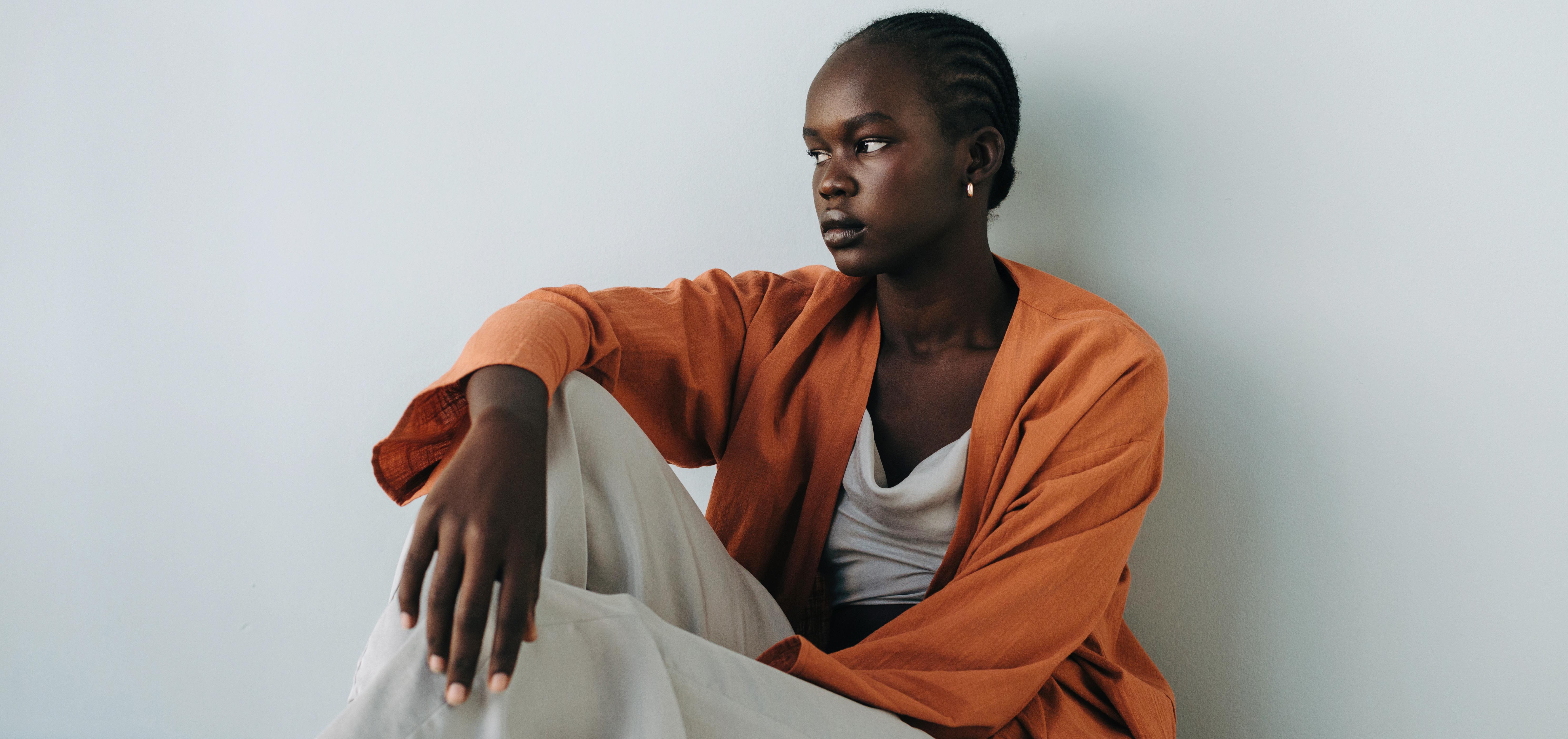 pensive woman sitting against a wall