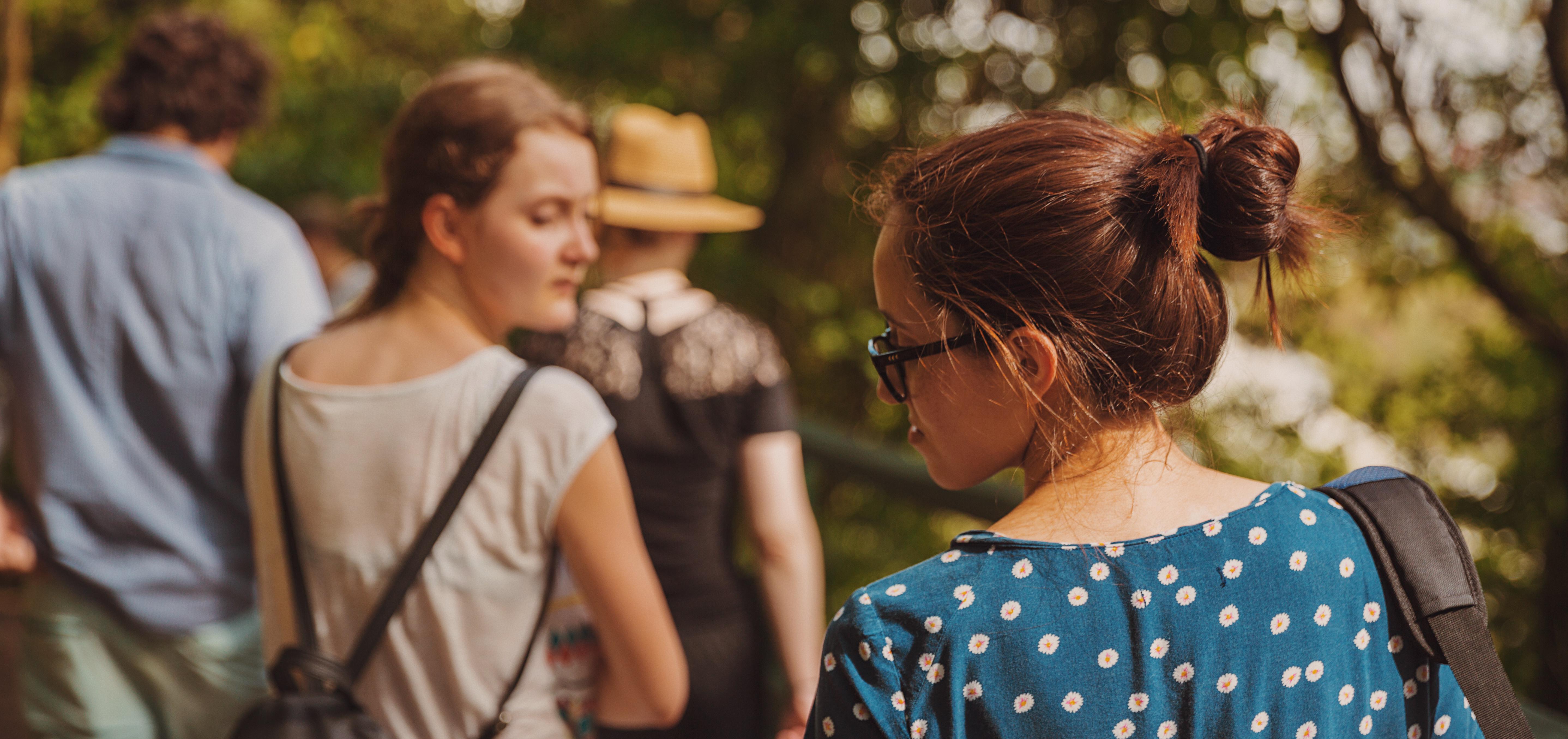 woman trailing behind a group of people on a walk