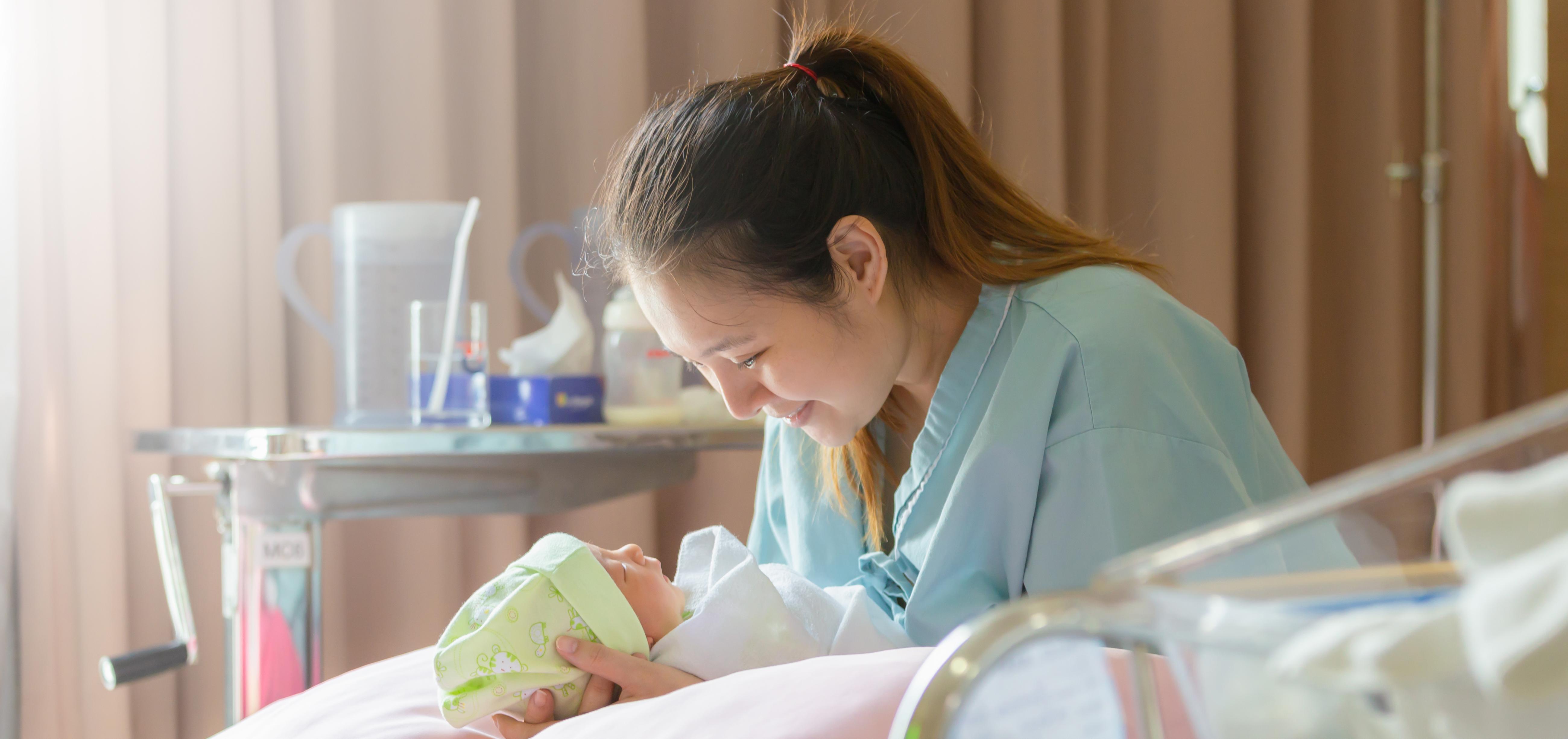 mother holding her baby in a hospital room bed