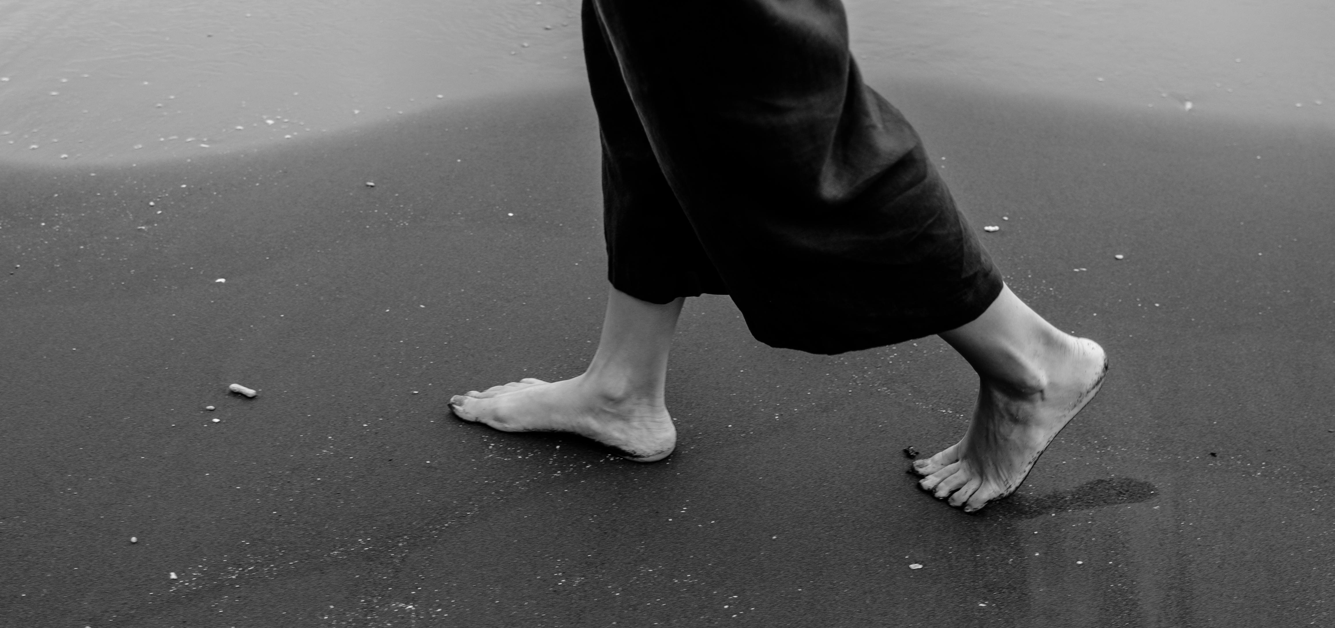 A woman walking on an empty beach in black and white