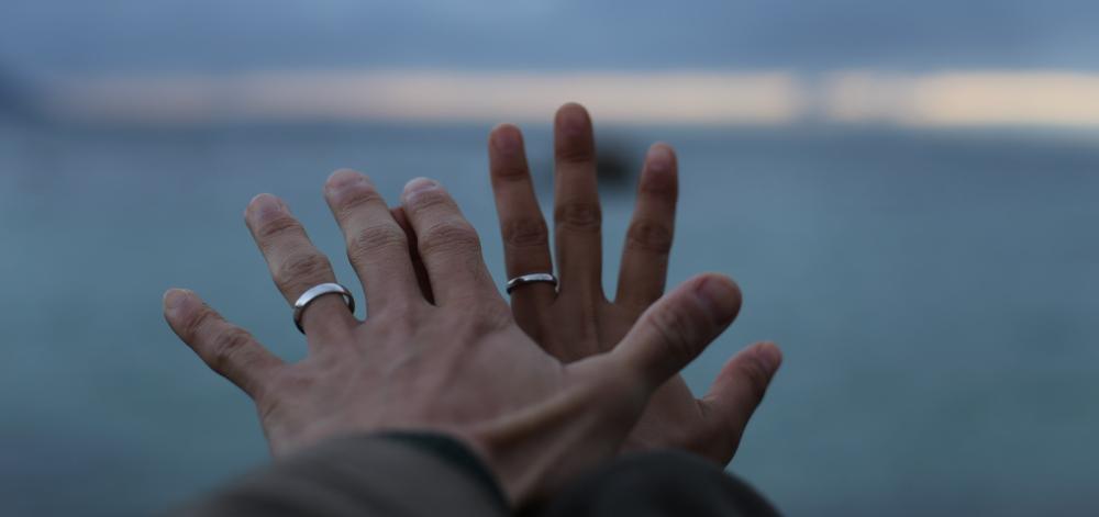 Two hands with silver rings reaching out into the distance